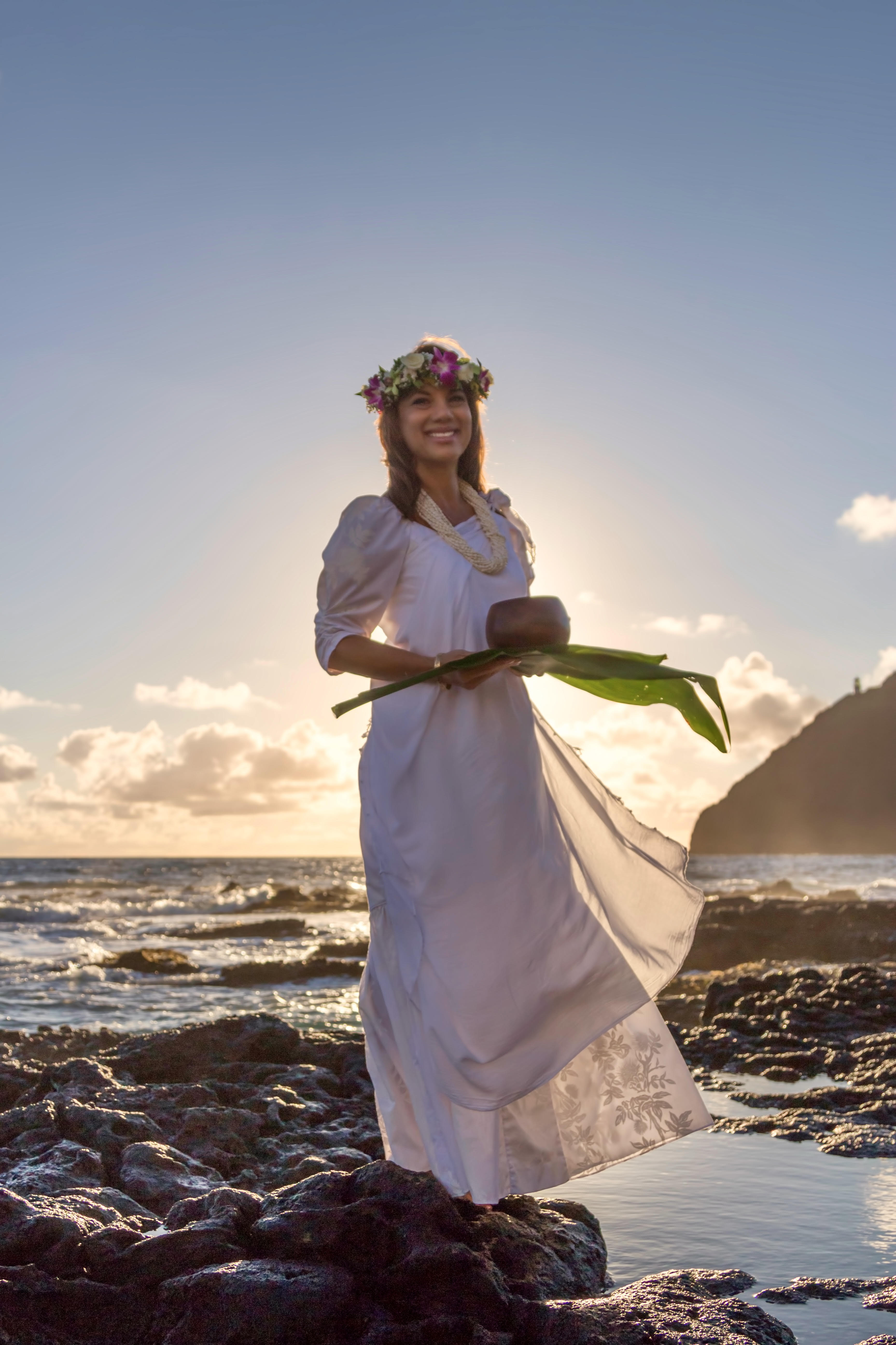 Kahu Pomaikai standing in a tide pool with the sun rising behind her